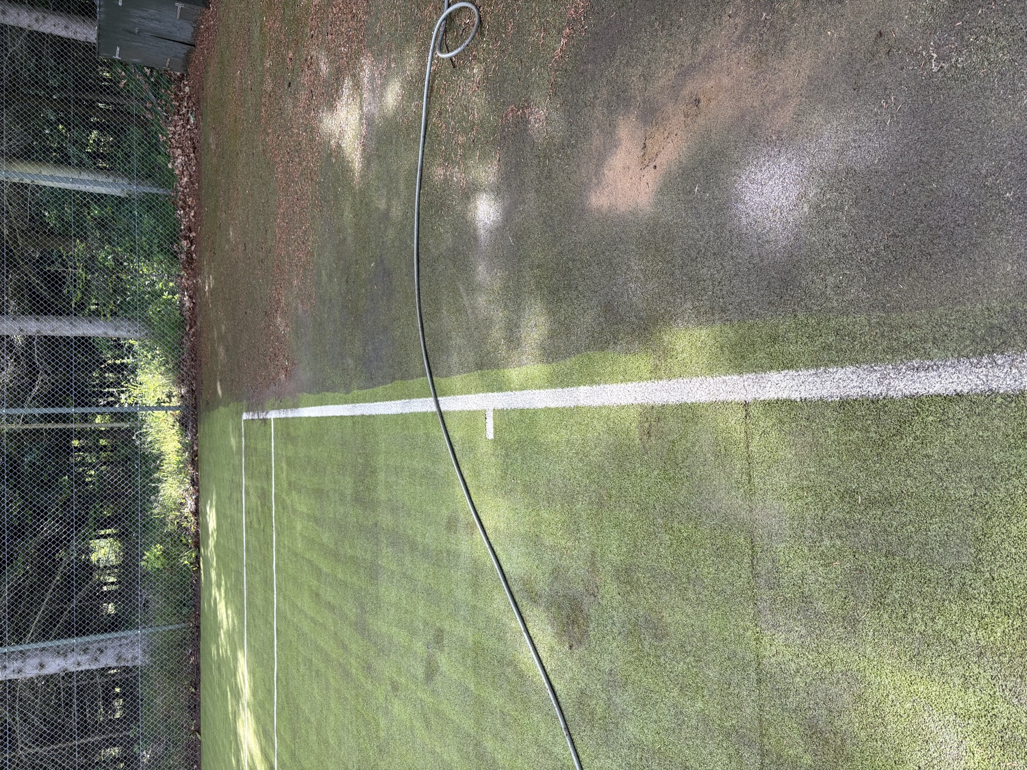 Cleaning process in action — hose and equipment on the court