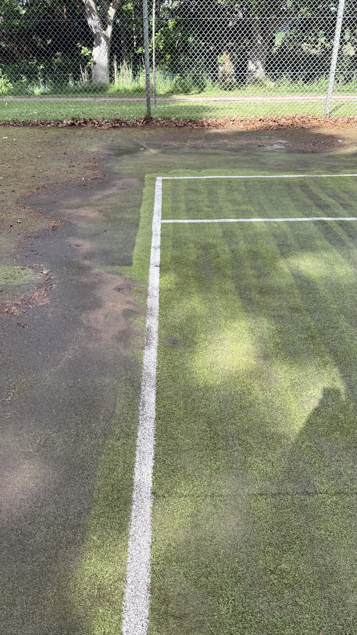 Tennis court half cleaned — black on the left, clean green on the right